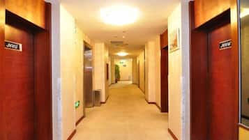 Un pasillo de hotel con puertas de madera, cada una identificada con un número de habitación.