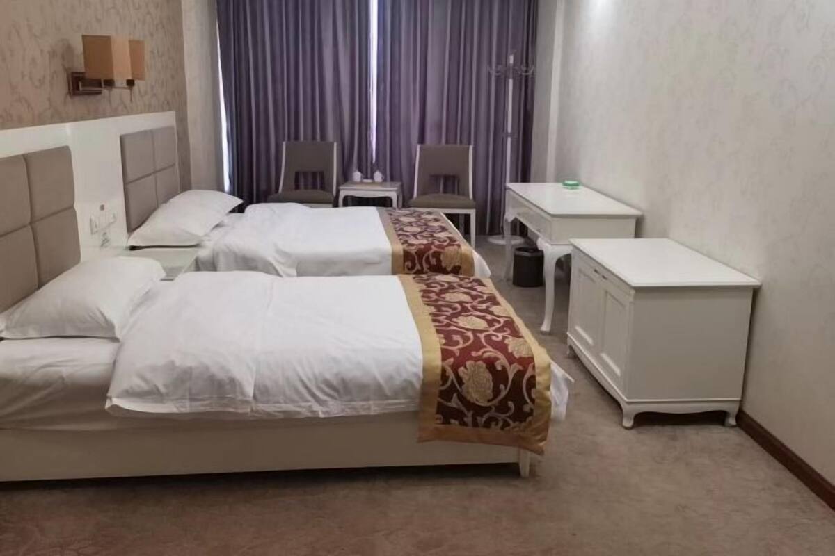 Een hotelkamer met twee bedden, een bureau en een stoel.