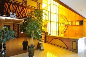 Un vestíbulo con una planta grande en maceta, un mostrador de recepción y una pared decorativa con un diseño circular.