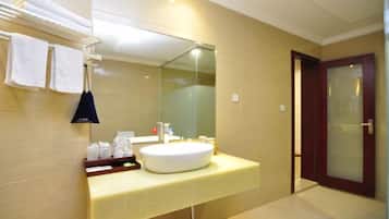 Un baño con lavamanos, espejo, toallero y una puerta.