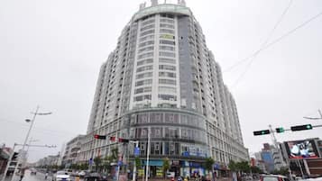 Un edificio de varios pisos con fachada curva, situado en una concurrida intersección con semáforos y señales de tráfico.