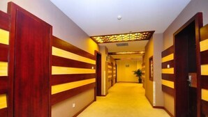 Corredor de hotel com painéis de madeira e piso carpeteado.