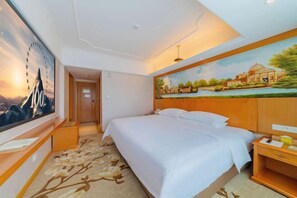 Ein Hotelzimmer mit einem großen Bett, einem Schreibtisch und einem Gemälde an der Wand.