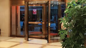 A revolving door with glass panels and a metallic frame, leading to a lobby area with a tiled floor and a potted plant. - Vienna Classic Hotel(Westlake Honghua Lake Scenic Area Branch,Huizhou) (Huizhou)