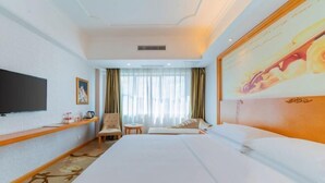 A hotel room with a large bed, a TV mounted on the wall, a small table, a chair, and a window with curtains. - Vienna Classic Hotel(Westlake Honghua Lake Scenic Area Branch,Huizhou) (Huizhou)