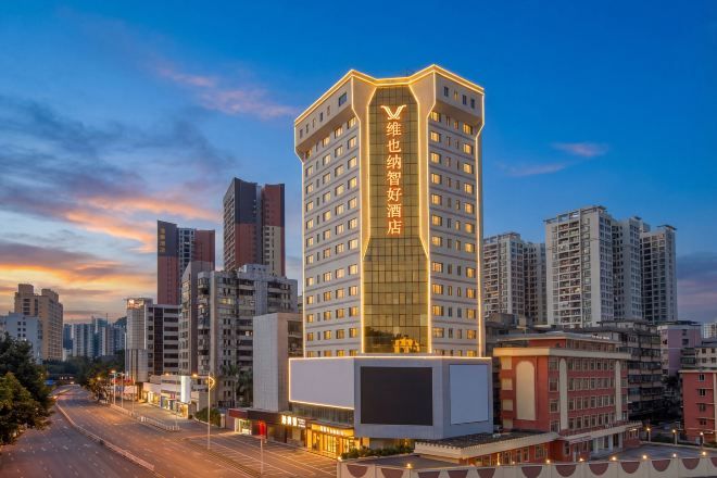 Un hôtel à plusieurs étages, doté d’une enseigne verticale bien visible, et entouré d’autres immeubles de grande hauteur.