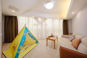 A hotel room with a sofa, a small table, curtains, and a tent-like structure.