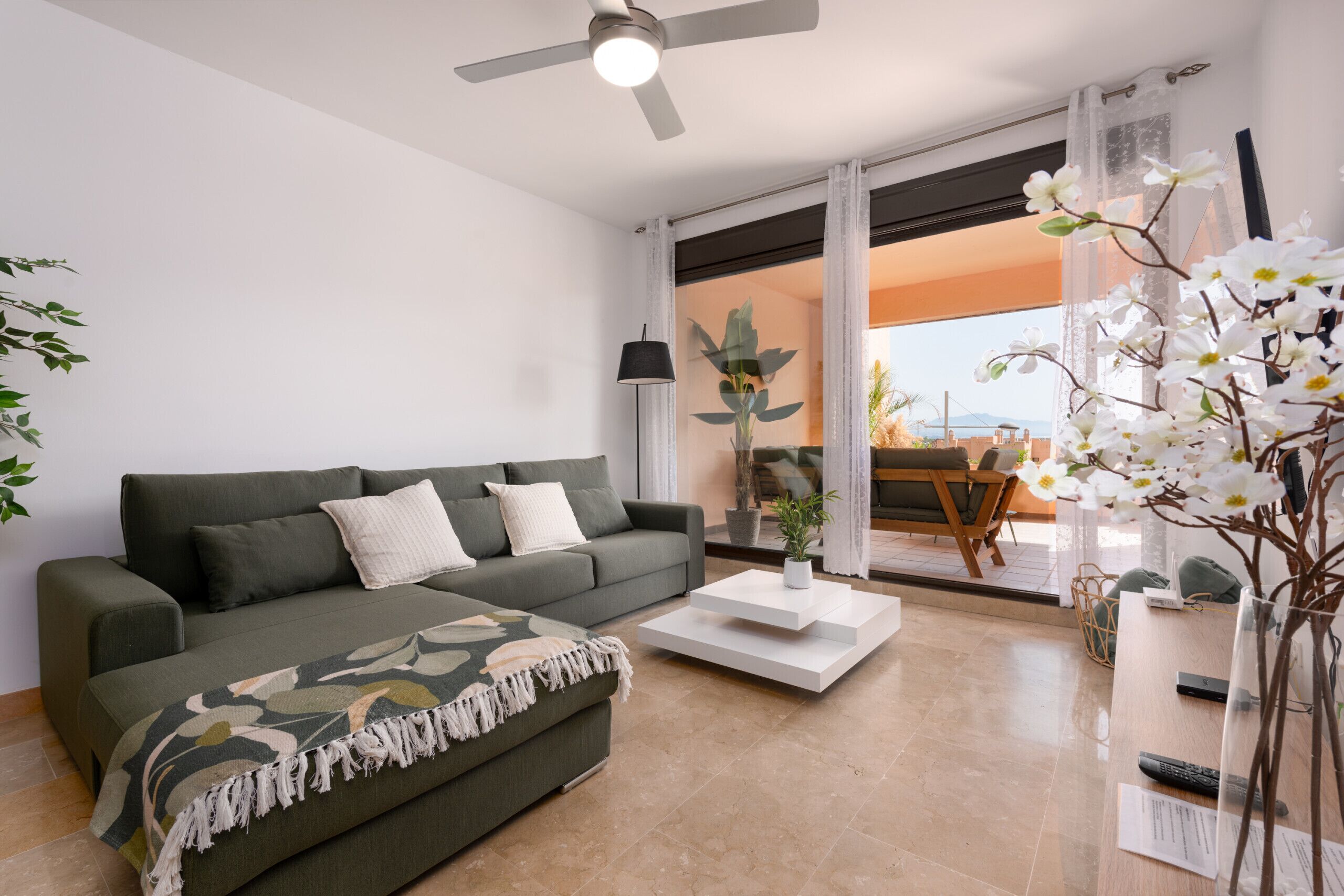 A modern living room with a sofa, coffee table, and a view of the outdoors.