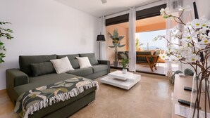 Ein modernes Wohnzimmer mit Sofa, Couchtisch und Blick ins Freie.