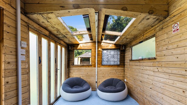A room with wooden walls, a skylight, two bean bags, and a 'No Smoking' sign.