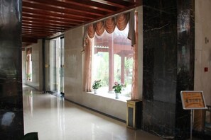 A corridor with a polished floor, a window with curtains, and a sign on the right. - Jinshan Hotel (Danfeng)
