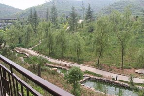 A view of a landscaped area with a pathway, a small water feature, and trees. - Jinshan Hotel (Danfeng)