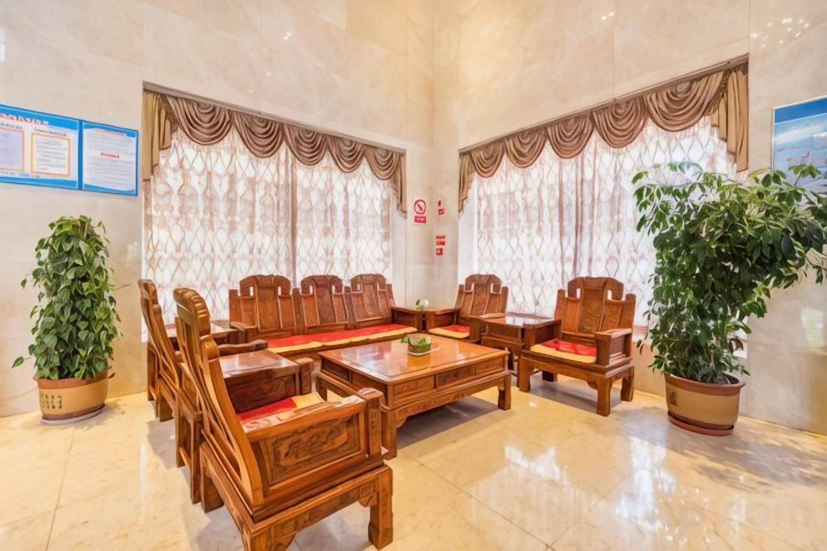 A lobby with a wooden reception desk, seating area, and potted plants.