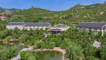 A large building complex surrounded by lush greenery and a body of water.