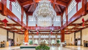 Un'ampia hall con un grande lampadario, travi in legno e un elemento decorativo al centro.