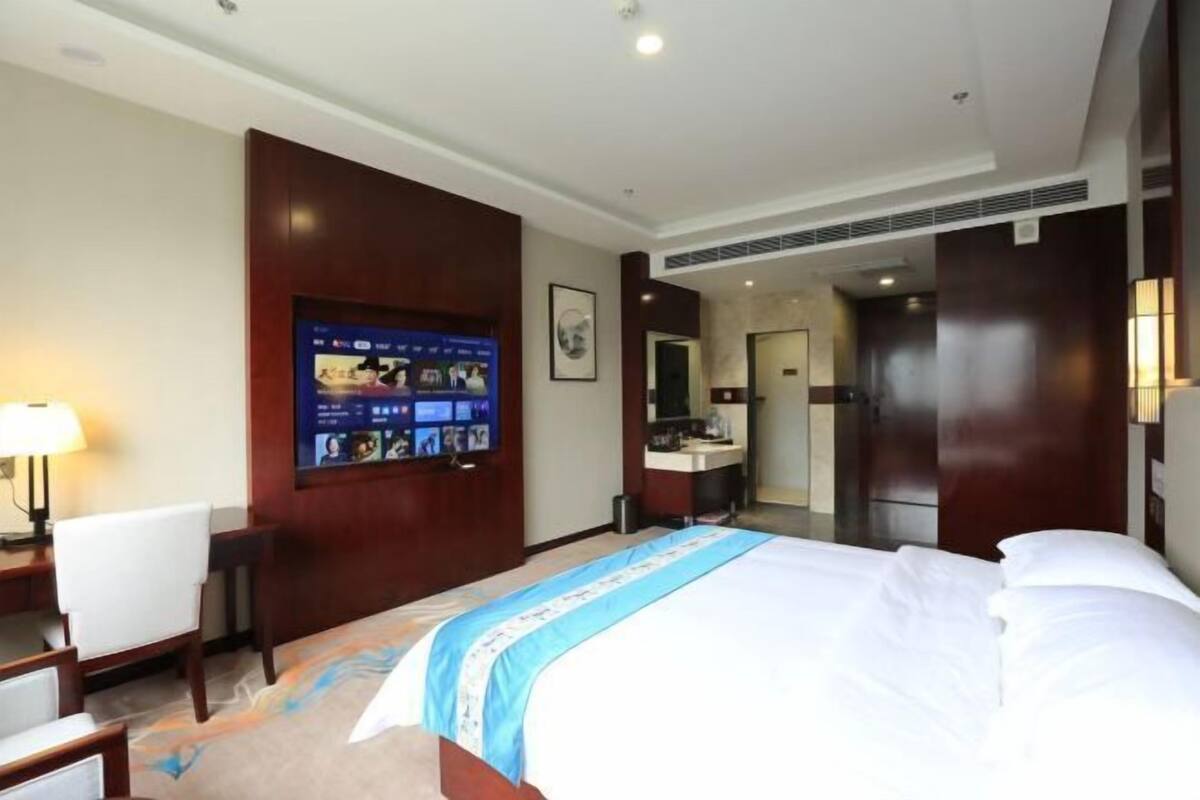 Hotellihuone, jossa on sänky, työpöytä, televisio ja kylpyhuone.