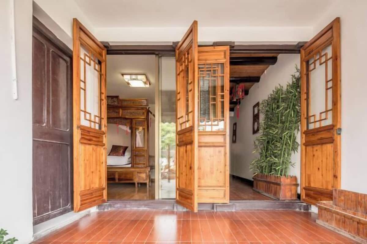 Uma porta de madeira tradicional com um painel de vidro deslizante, piso de azulejos e um vaso de planta.