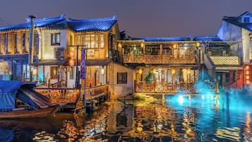 Un edificio tradicional de varios niveles, con un canal de agua en primer plano y una embarcación amarrada a la entrada.
