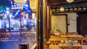 Ένα παραδοσιακό ξύλινο τραπέζι με τσαγιέρες και ένα φυτό σε γλάστρα.