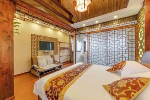 A hotel room with a bed, a sofa, a TV, and a decorative screen. - Qianshe Guanshuiyi Riverside Boutique Inn (Kunshan)
