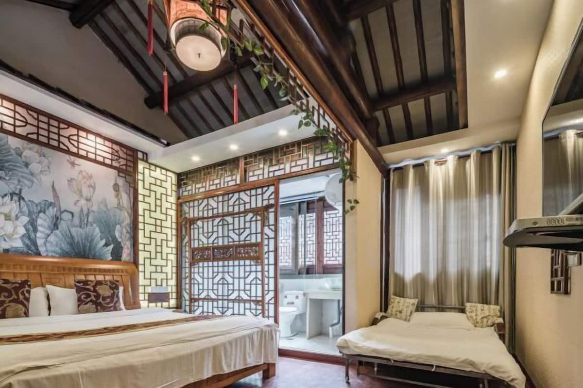 Quarto em estilo tradicional com duas camas, parede decorativa com um mural floral e uma porta deslizante para um banheiro.
