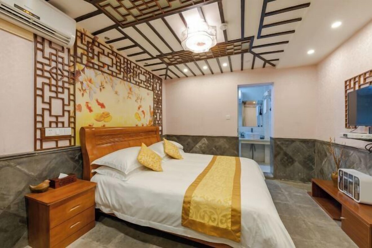 A hotel room with a bed, wooden nightstand, and a mirror.