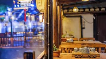 Un comedor interior con mesas y sillas de madera, faroles tradicionales y vista a la calle.
