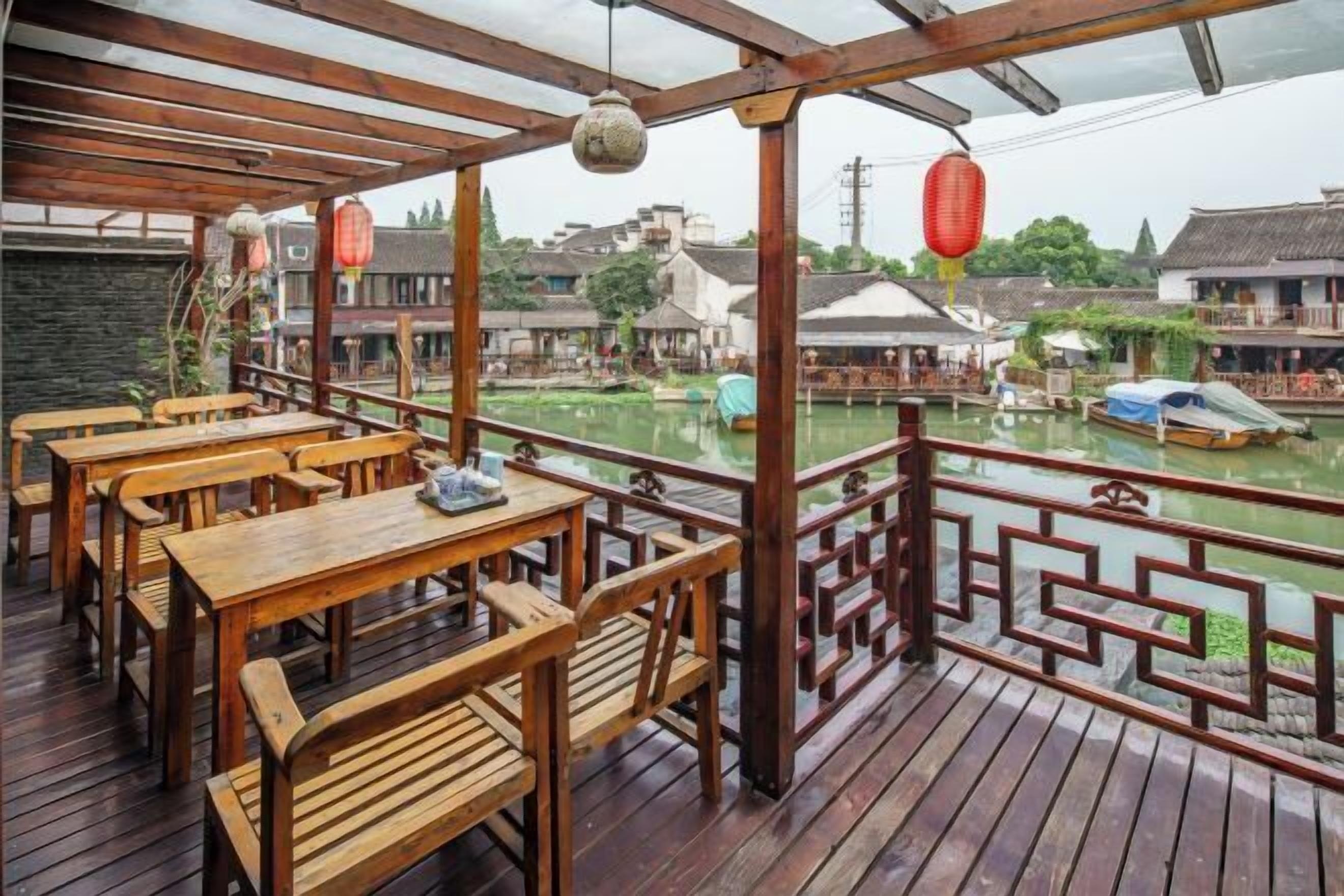 A wooden deck with tables and chairs overlooking a canal with traditional buildings.