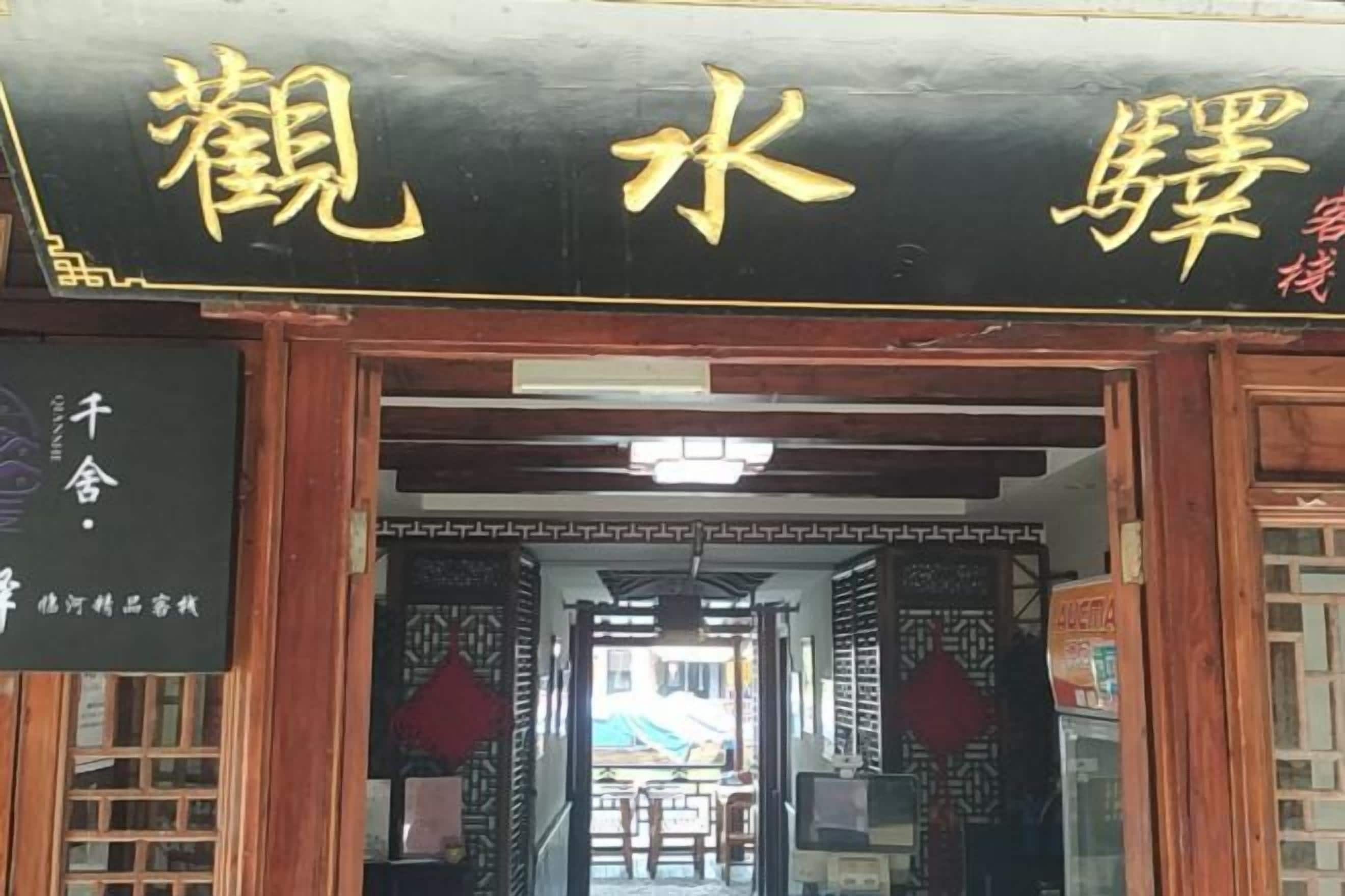 Entrada de un edificio tradicional chino con fachada negra y caracteres chinos dorados.