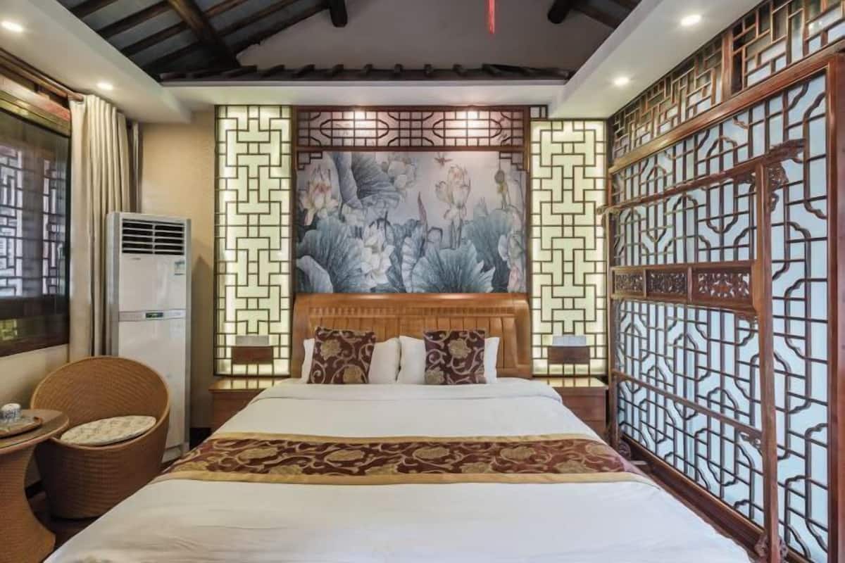 Quarto de hotel com cama, ar-condicionado fixado na parede, cabeceira decorativa e divisória de estilo tradicional.