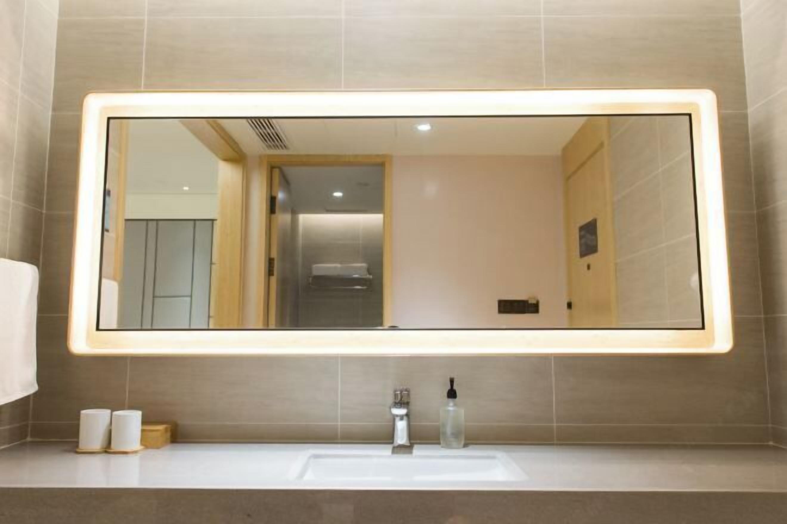 A bathroom with a large mirror, a sink, and a toilet.
