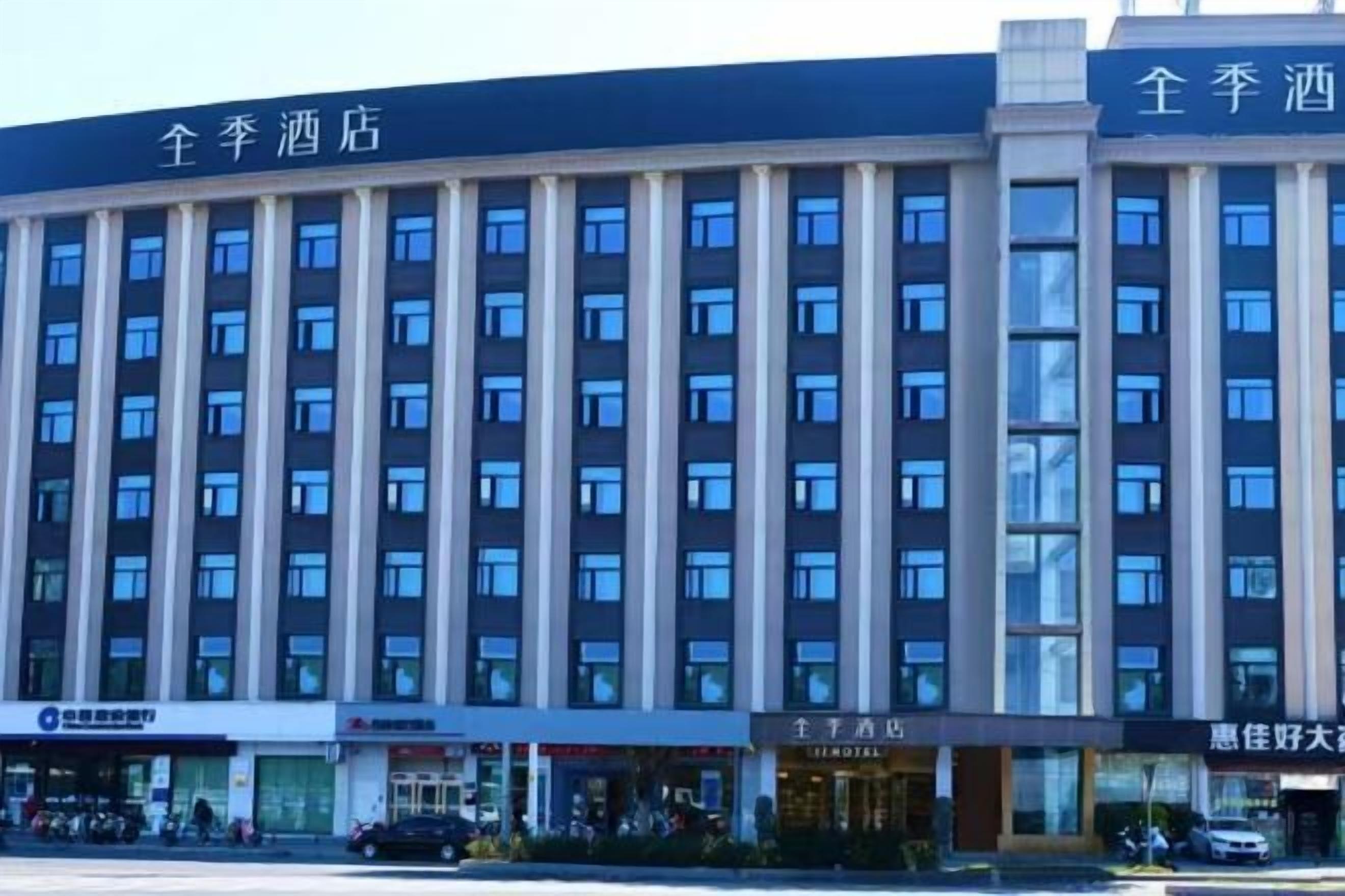 A multi-story hotel with a modern facade, featuring a series of windows and a prominent signage at the top.