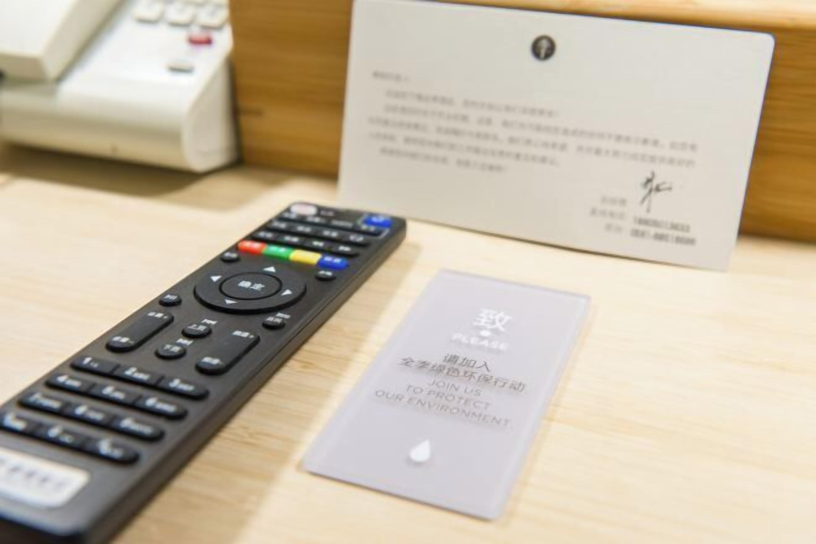 A remote control, a card, and a wooden surface.