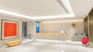A modern reception area with a reception desk, a digital screen, and a wooden bowl on the floor. - JI Hotel (Fuzhou Gushan Fuma Road) (Fuzhou)