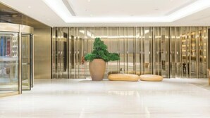 A modern lobby with a glass storefront, a large potted plant, and a seating area with cushions. - JI Hotel (Fuzhou Gushan Fuma Road) (Fuzhou)