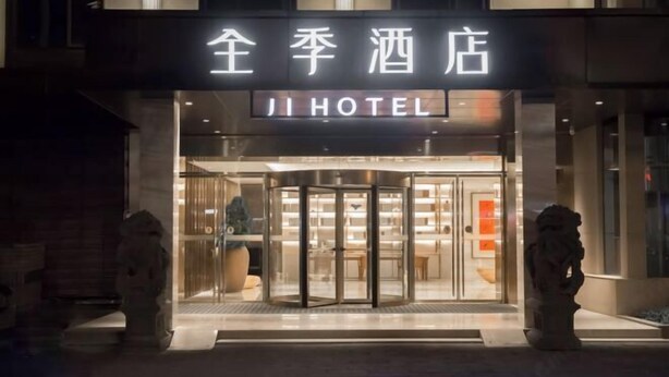 A hotel entrance with a revolving door, a sign above the door, and two stone lion statues on either side. - JI Hotel (Fuzhou Gushan Fuma Road) (Fuzhou)