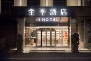A hotel entrance with a revolving door, a sign above the door, and two stone lion statues on either side. - JI Hotel (Fuzhou Gushan Fuma Road) (Fuzhou)