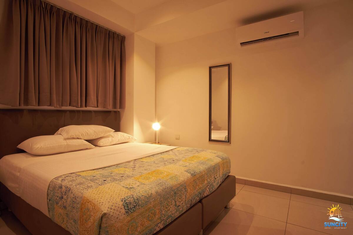 Une chambre à coucher comprenant un lit, une lampe de chevet, un miroir et un appareil de climatisation.