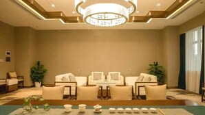 Amplia habitación con una zona de estar central, un candelabro y una mesa de comedor dispuesta con vajilla de té.