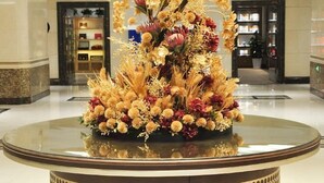 Un vestíbulo con una mesa redonda de vidrio que presenta un arreglo floral.