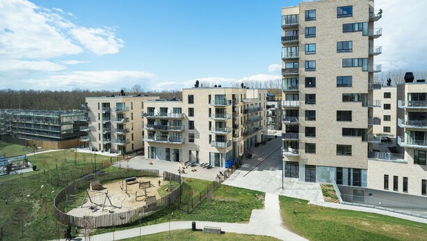 A modern apartment complex with multiple floors, balconies, and a central courtyard with playground equipment. - Top-class 1-bedroom Apartment in Odense (Odense)