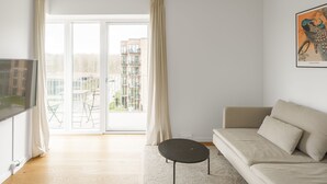 A modern living room with a sofa, a small round table, and a TV. - Top-class 1-bedroom Apartment in Odense (Odense)
