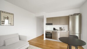 A modern kitchen with stainless steel appliances, a dining area with a table and chairs, and a living area with a sofa. - Top-class 1-bedroom Apartment in Odense (Odense)