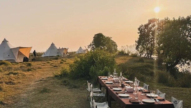 A dining table set outdoors with tents in the background. - Burhan Wilderness Camps (Manjhara)