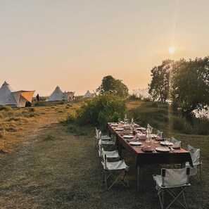 Ein Esstisch im Freien, im Hintergrund Zelte.