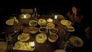 A dinner table set with various dishes and glasses, illuminated by candles. - Burhan Wilderness Camps (Manjhara)