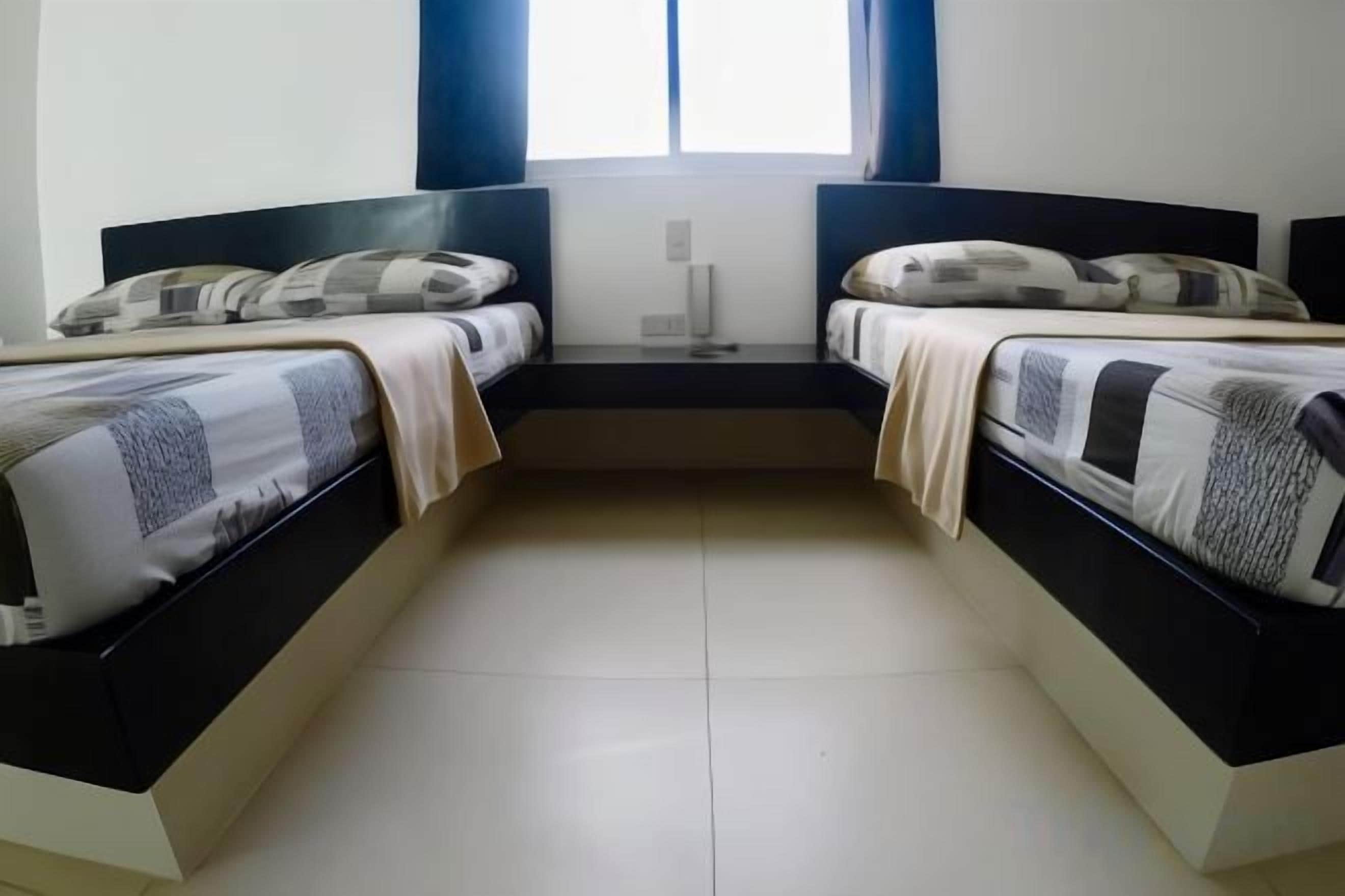 Une chambre double avec deux lits, une fenêtre et une table de chevet.