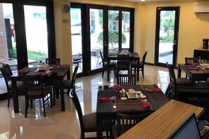 A restaurant with multiple tables and chairs, large windows, and a clean, tiled floor. - Jinjiang Inn - Boracay Station 1 (Boracay Island)