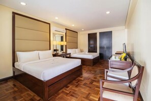 Une chambre d’hôtel avec un grand lit, un lit plus petit, un bureau et une chaise.