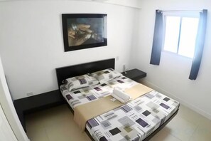 A bedroom with a bed, a nightstand, a wall-mounted painting, and a window with curtains. - Jinjiang Inn - Boracay Station 1 (Boracay Island)